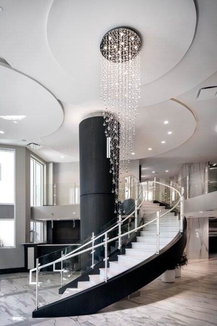 interior photograph of the luxury Seaglass condominium's lobby with a floating staircase, glass railing, and crystal chandelier